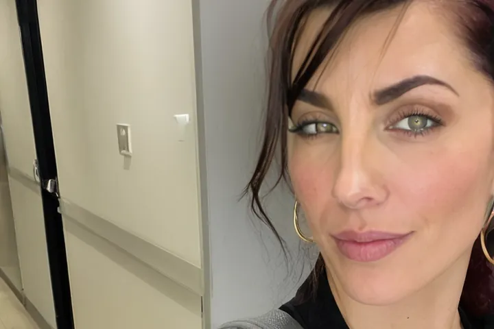 Woman in a black zip jacket taking a selfie in a hallway, decorative image